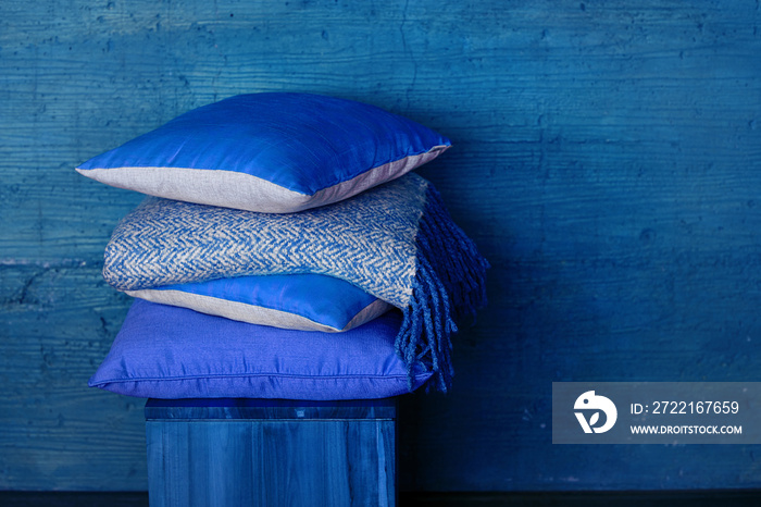 Pillows on chair against blue wall.