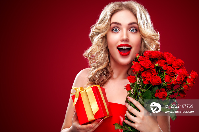 Beautiful blonde woman holding bouquet of red roses and gift. Saint Valentine and International Wome