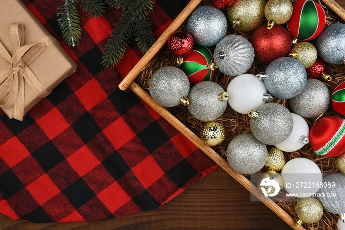 Christmas Flat Lay - Wood Box of Christmas Tree Ornaments on a plaid trre skirt with present and pin