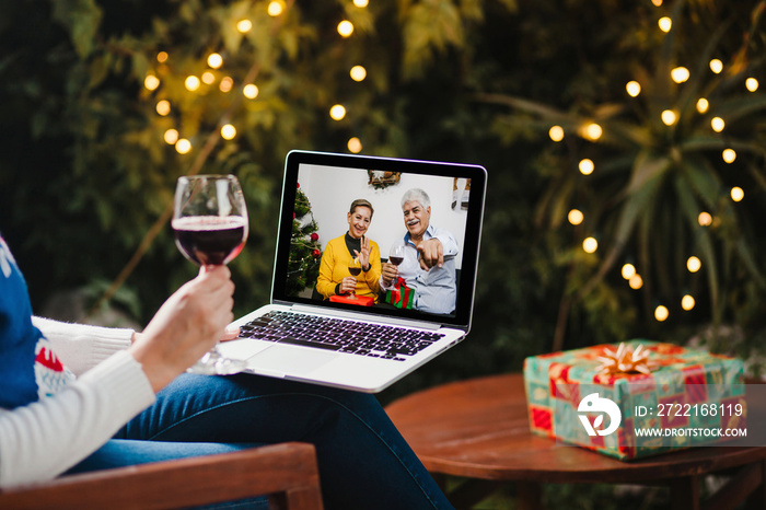 Latin parents with hispanic daughter with wineglass on Christmas video call