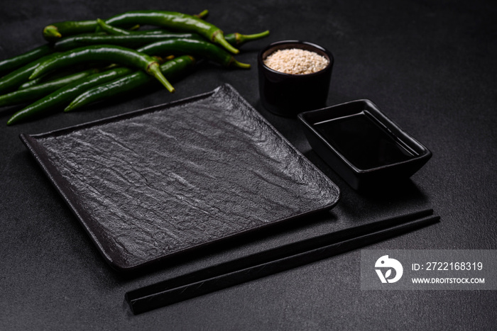 Empty plate with wooden sticks for Asian food on a dark concrete background