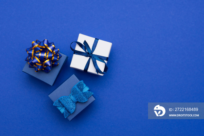 blue gift boxes with gold bow - top view - on classic blue background, copy space