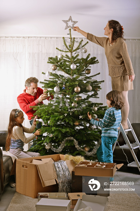 Familie dekoriert Weihnachtsbaum im Wohnzimmer
