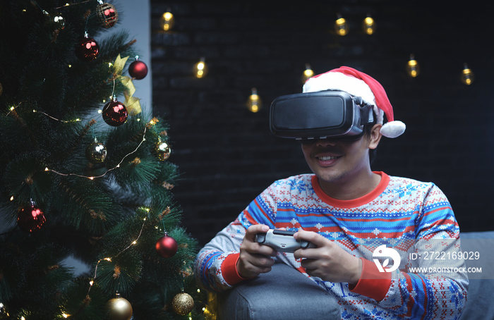 Asian Man With Christmas Costume Playing Virtual Reality Sitting Beside Christmas Tree
