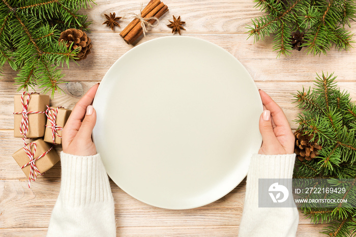 girl hand hold Top view. Empty white plate on wooden background with christmas decoration. New Year 