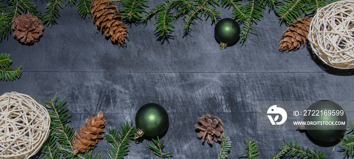 Frame of natural fir pine branches and cones with green baubles and beige deco rattan balls on rusti