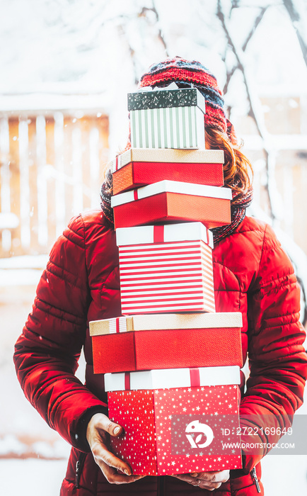 woman returning home from shopping holding pile of christmas present boxes