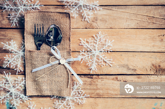 christmas table place setting and silverware, snowflakes on wooden background with space.