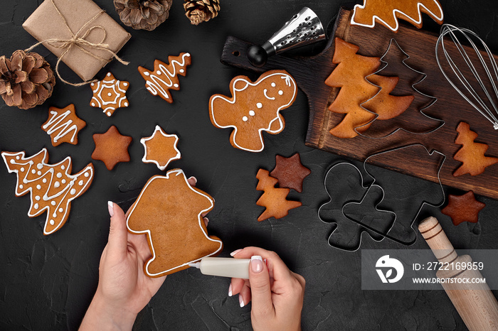 Woman decorating gingerbread Christmas cookies with icing sugar. Christmas preparations concept. Top