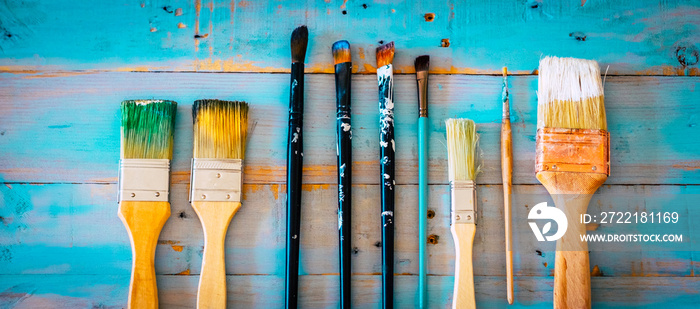 Set of paint brushes for artist and decorator on a blue wooden table - concept of art and work at home - above view - dirty of colors for a beautiful nice background