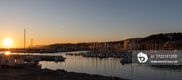 Beautiful sunset panoramic view of a port at sunset with multiple sailboats. Arenys de Mar village in El Maresme coast, Barcelona.