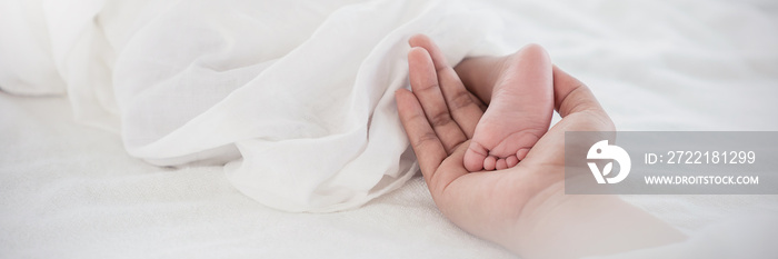 Close up mother’s hands holding black African newborn baby feet. Closeup feet of newborn baby. Healthcare and medical love lifestyle mother or father’s day background concept