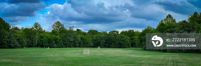 Panorama of a lawn in a park used for playing recreational lacrosse games. Several goals spread in different parts of the grass space.