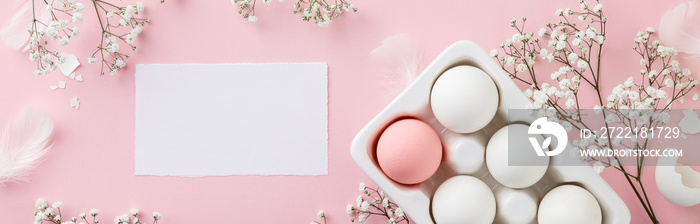 Easter eggs in white ceramic holder and flowers on pink background