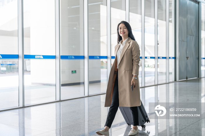 商务女士在机场拉着行李箱