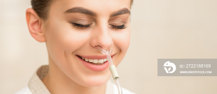 Beautiful happy young caucasian woman receiving nasal inhaler with essential oil smiling in a spa