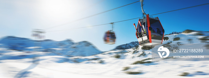 ski lift gondolas against blue sky over snowy mountains at ski resort at Italy Alps on sunny winter day. banner copy space