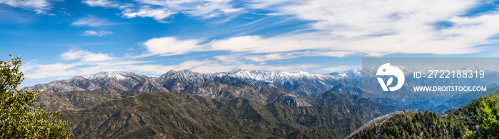 Panoramic view of Angeles National Forest on a sunny day; mountains covered in snow in the background; Los Angeles county, south California