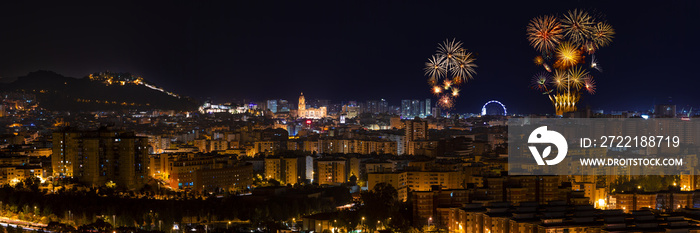 Panoramic aerial view to illuminated Malaga city at night and fireworks blowing in the sky