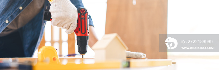 Closed up hand of carpenter using drill at workshop banner size background