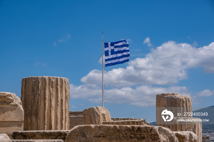 Athens, Greece. Greek flag and ancient column remains in Acropolis against blue sky background