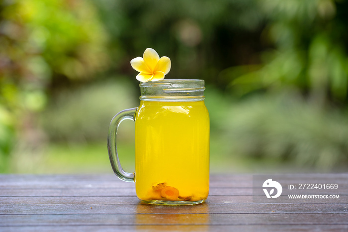 Energy tonic drink with turmeric, ginger, lemon and honey in glass mug, nature background, close up