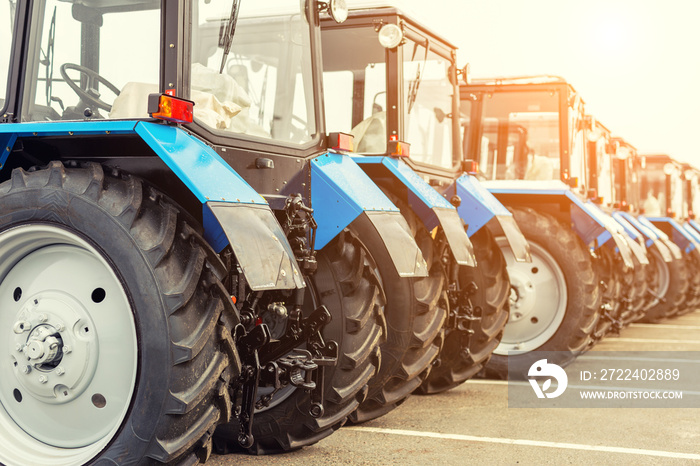 Many different tractors standing in row at agricultural fair for sale outdoors.Equipment for agriculture.Heavy industrial machines presented to an agricultural exhibition