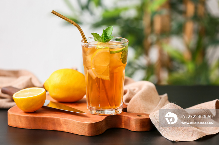 Glass of tasty ice tea with lemon on table against blurred background