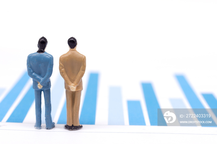 Miniature figures businessmen standing on a graph chart financial