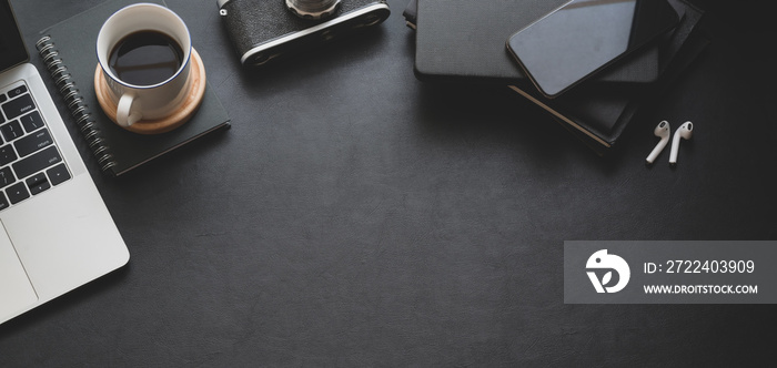 Top view of dark trendy workspace with laptop computer, coffee cup and office supplies