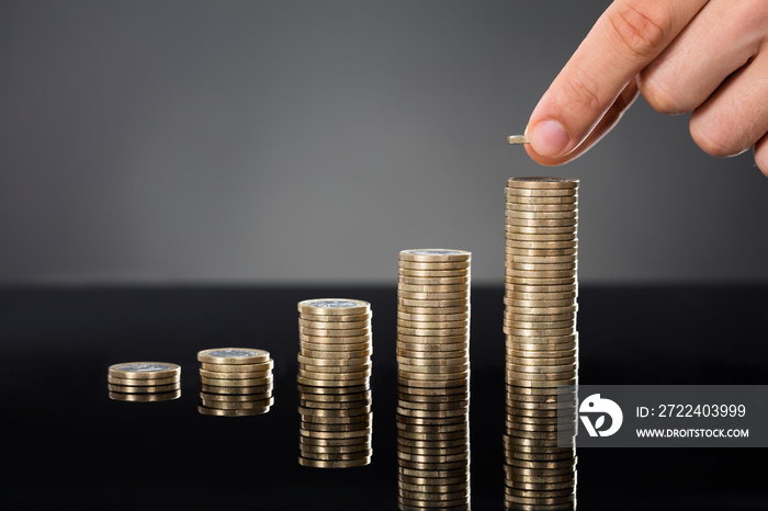 Person Stacking Coins On Desk