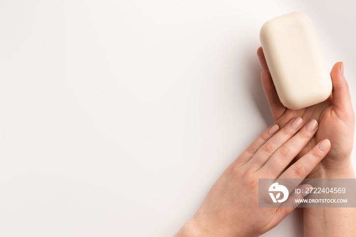 Female hands with bar of natural soap isolated, on white background. Flat lay, top view, copy space.