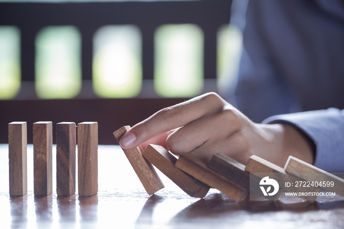 Businessman stopping domino effect with his finger. Business crisis concept.