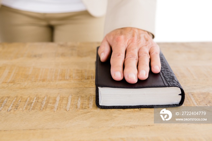 Midsection of woman with hand on bible