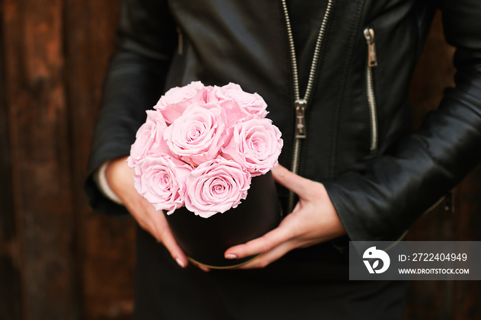 Young girl holding tender pink roses in black gift box