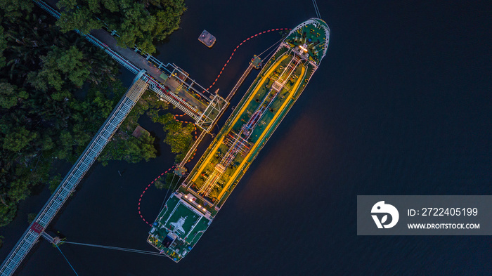 Aerial view Crude oil tanker under cargo operations on typical shore station with clearly visible mechanical loading arms and pipeline infrastructure. Thailand harbor.