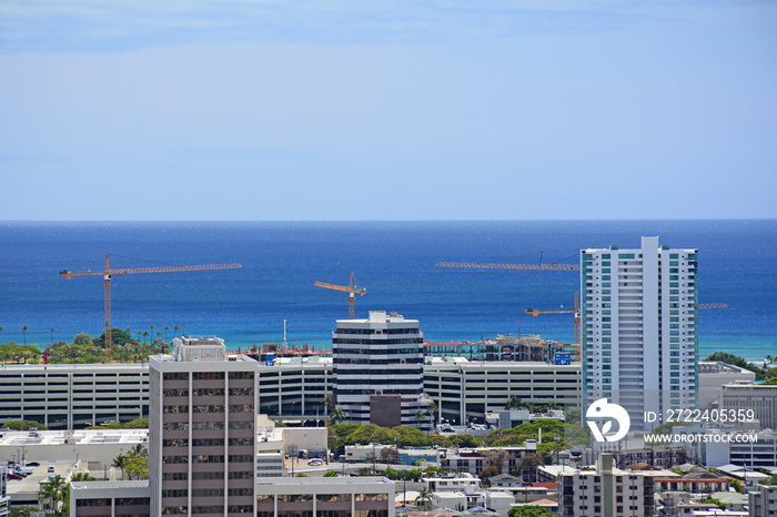 Pacific ocean view with multiple cranes under construction near Ala Moana Beach area of Honolulu on Oahu, Hawaii.