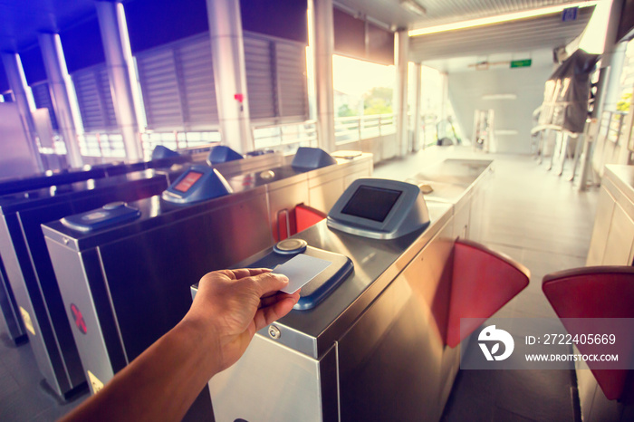 Selective focus to hand of passenger using smart card to open automatic gate machine at sky train station. Modern automatic ticket.