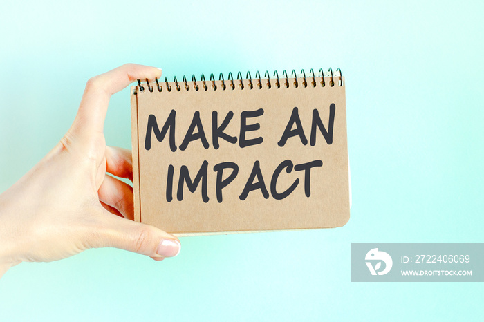 woman holding a card with a message text MAKE AN IMPACT