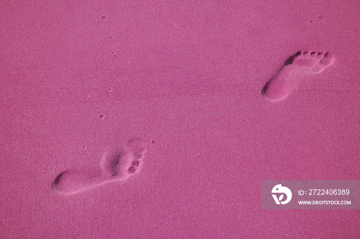 Pop art styled woman’s walking footprints on the sand beach in magenta color