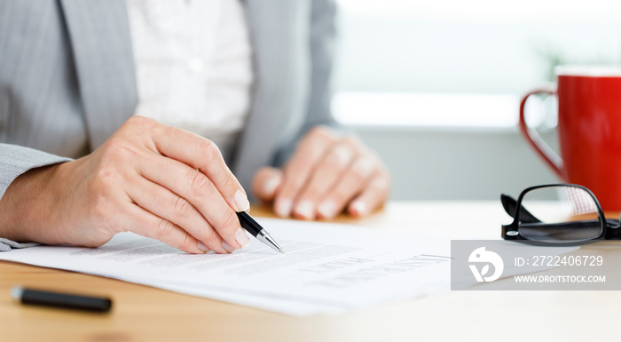 Close-up shot of businesswoman filling out insurance policy in her office