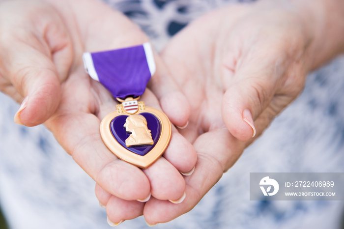 Senior Woman Holding The Military Purple Heart Medal In Her Hands.