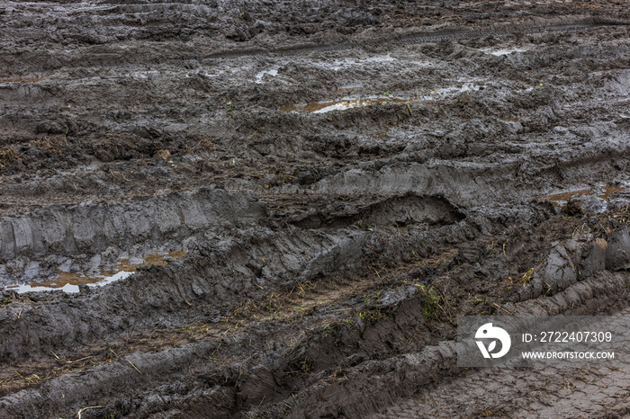 Black wet dirt road with puddles of dirty water at day light