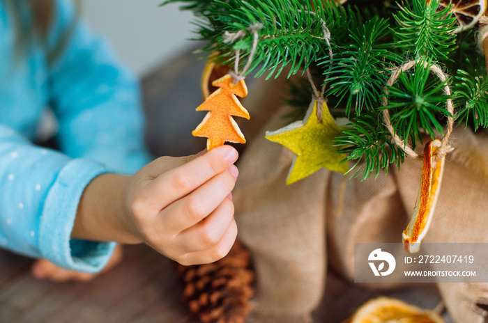 Kids hand holding dried citrus slice decoration on the Christmas tree