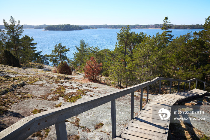 Wooden stairs leading down from the rocks towards the sea. sunny spring day at Finnish archipelago in the Kemiö Island, Finland.