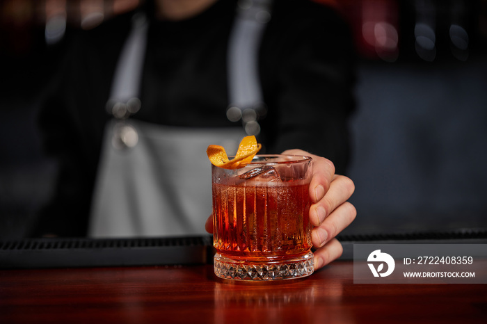 Barman holding out glass with alcoholic cocktail