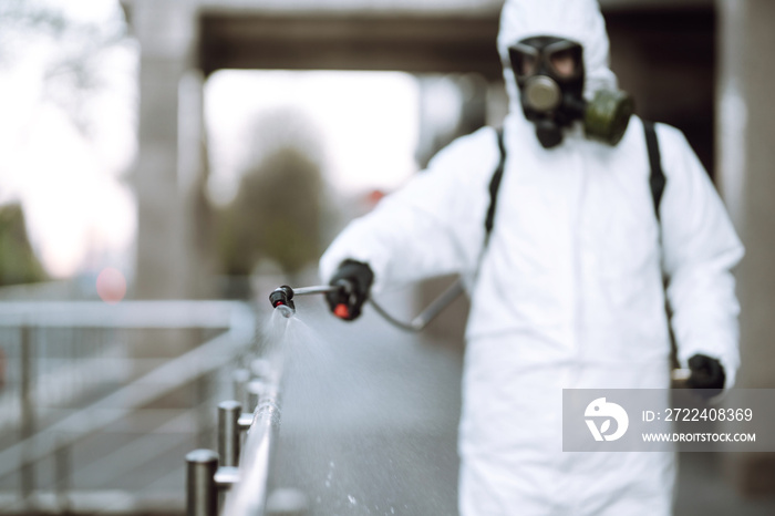 Disinfectant sprayers with spray chemicals onto the railing in the empty public place at dawn in the city of quarantine. Covid -19. Cleaning concept.