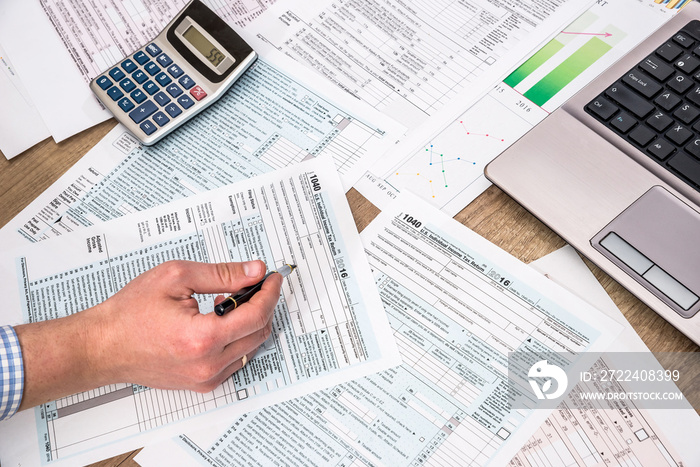 Businessman  filling 1040 tax form with help laptop at office desk