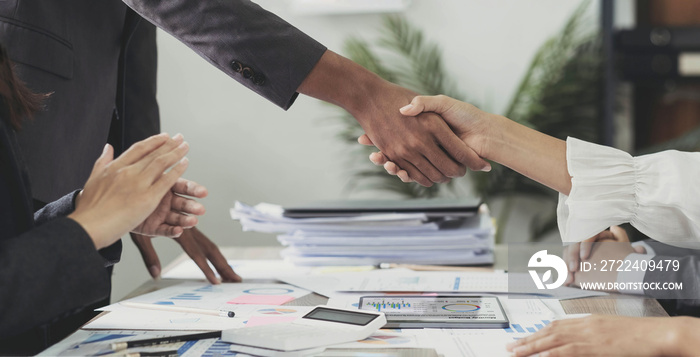 Group business people handshake at meeting table in office together. Young businessman and businesswoman workers express agreement of investment deal..