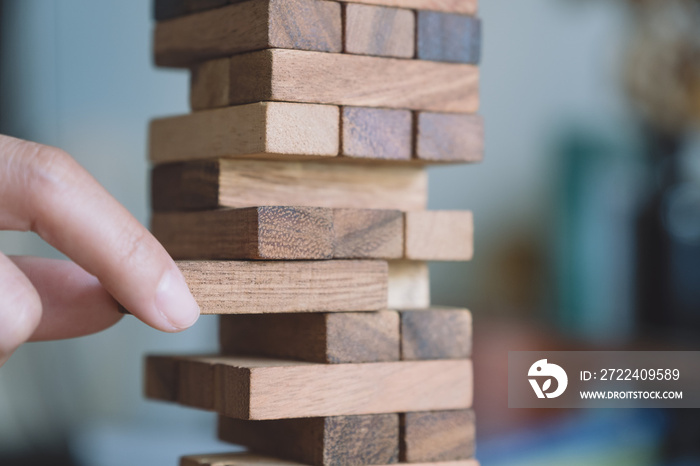 Closeup image of a hand holding and playing Tumble tower wooden block game